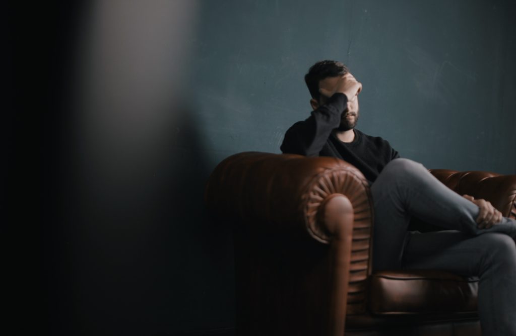 Stress man sitting on sofa against wall